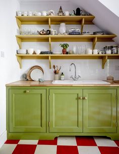 a kitchen with green cabinets and red checkered flooring