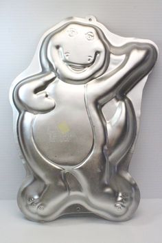 a silver monkey shaped cake pan sitting on top of a white countertop next to a wall