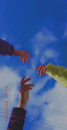 four hands reaching up into the blue sky