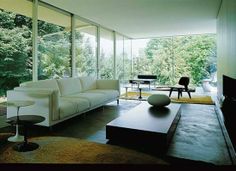 a living room filled with white furniture and lots of glass doors leading to trees in the background