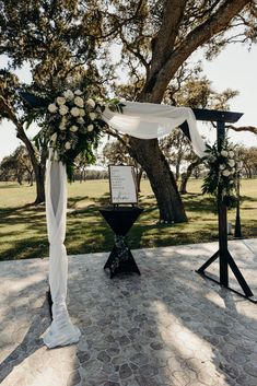 an outdoor ceremony setup with white flowers and greenery