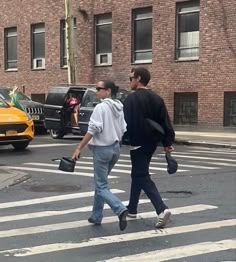 two people crossing the street in front of some cars