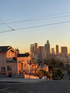 the sun is setting over a city with tall buildings and power lines in the foreground