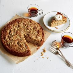 a piece of cake on a plate next to some cups and spoons