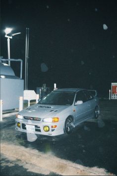 a white car parked in front of a gas station