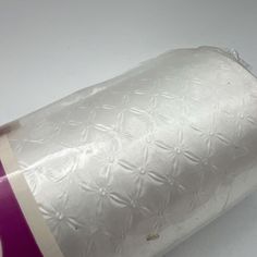 a roll of toilet paper wrapped in plastic on top of a white tablecloth covered surface