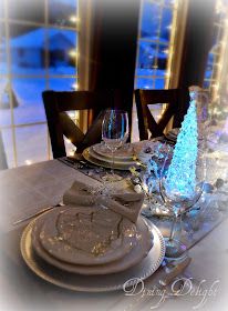 the table is set with white plates, silverware and blue christmas tree decorations on it