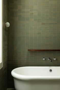 a white bath tub sitting in a bathroom next to a shelf with towels on it