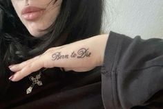 a woman with a tattoo saying born to be on her left hand and the words born to be written in cursive font