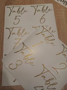 two sheets of white paper with gold ink on them and some type of table numbers