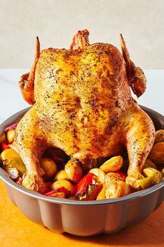 a whole chicken in a pan with roasted vegetables