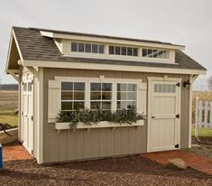 a small shed with windows and plants in the window sill on top of it