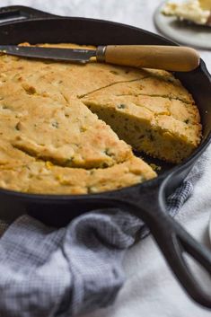 a cake in a pan with a spatula on the side and a piece missing from it