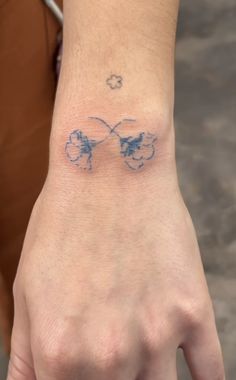 a person's hand with a tattoo on the wrist that has two butterflies drawn on it