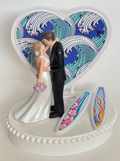 a figurine of a bride and groom kissing in front of a surfboard