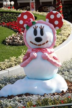 a minnie mouse statue in the middle of a flower garden