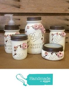 four jars with flowers painted on them are sitting on a table next to a wall