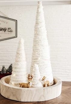 three white christmas trees sitting on top of a wooden tray