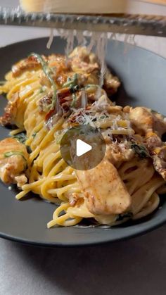 a black plate topped with pasta covered in sauce