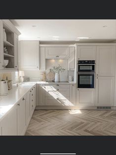 a kitchen with white cabinets and wood flooring