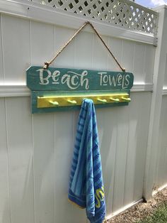 a towel hanging on the side of a white fence next to a blue and yellow towel