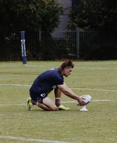 a man kneeling down on top of a field holding a white frisbee in his hand