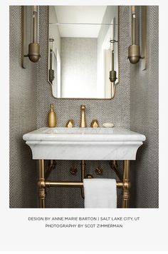 a white sink sitting under a bathroom mirror next to a wall mounted faucet