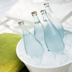 three bottles of water sitting in an ice bucket on top of a green towel next to some towels