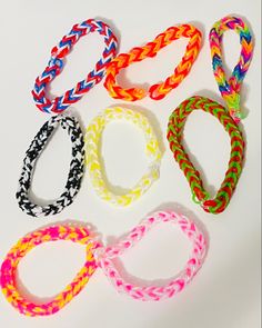 six different colored bracelets on a white surface with one knoted in the middle