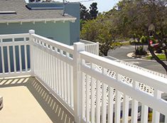 a balcony with white railings and blue houses in the background