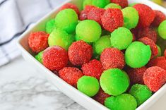 a white bowl filled with green and red candies on top of a marble counter