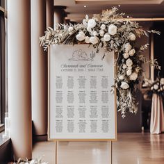 a wedding seating chart with white flowers and greenery