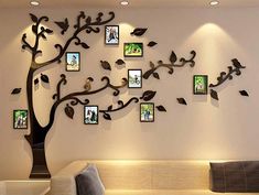 a tree with many pictures hanging on it's side and birds perched on the branches