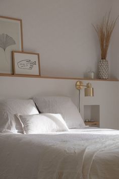 a bed with white sheets and pillows in a bedroom