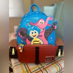 Hold On To Your Favorite Movie Moments With This Exclusive Loungefly Pixar Inside Out Bing Bong Wagon Mini Backpack. On The Front, Bing Bong And Joy Blast Off, Ready For Adventure-Leaving Behind A Trail Of Glitter And Rainbows. Embroidered Candies Spill Forth From The Wagon To Add A Burst Of Excitement. An Enamel Zipper Charm Of Balloons, In A Rainbow Of Colors, Tops Off The Look. Applique Flaps Stick Out Over The Wheels, Which Zip Open For Extra Storage And Convenience. On The Back, The Words, Fun Red Backpack Bag, Fun Travel Bag With Removable Pouch, Playful Red Backpack For Everyday Use, Playful Red Standard Backpack, Playful Travel Backpack, Inside Out Bing Bong, Bing Bong Inside Out, Pixar Inside Out, Bing Bong