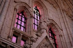 an old building with two windows and red light coming from the window sills