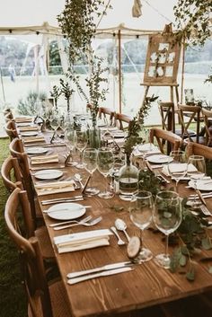 a long table set with place settings and greenery