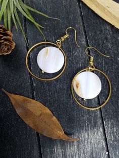 Who says shell jewelry is just for summer? These dangling hoop earrings feature gorgeous 20mm round natural white shell discs suspended within a 30mm gold-plated circle charm, and will transition effortless from season to season. The shell discs are 100% natural and may have some light brown inclusions. The ear wires are made of hypoallergenic gold-plated surgical steel. The full earrings, ear wires included, measure about 2 1/8 inches.These hoop earrings are extremely lightweight, each weighing White Circular Jewelry For The Beach, Round Metal Earrings For The Beach, Round Metal Earrings For Beach, Circle Earrings With Ear Wire For Beach, Full Earrings, Shell Hoop Earrings, Earrings Dangling, Dangle Hoop Earrings, Earrings Ear