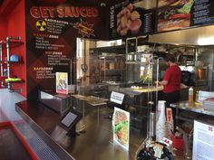 the inside of a fast food restaurant with menus on the wall and an employee working behind the counter