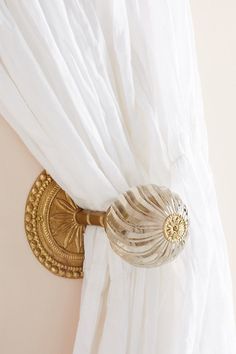 a white curtain with gold accents hanging from it's side