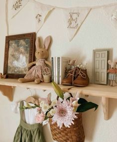 there is a shelf with some pictures and flowers next to a basket on the wall