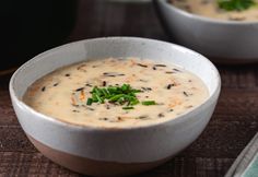 two white bowls filled with soup on top of a wooden table