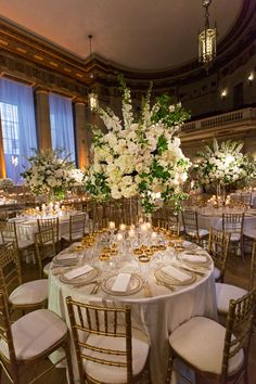 the tables are set with white flowers and gold rimmed glasses for an elegant centerpiece