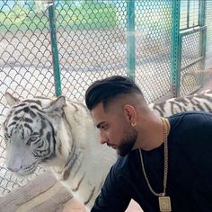 a man petting a white tiger in an enclosure