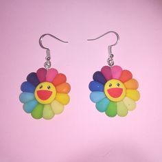 a pair of colorful flower shaped earrings on a pink background