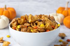 a white bowl filled with candy cornflakes and pumpkins next to other halloween treats