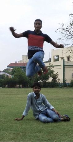 two young men are playing frisbee in the park