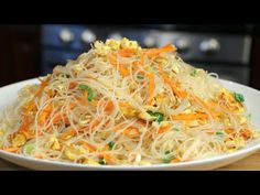 a white bowl filled with carrots and sprouts on top of a wooden table