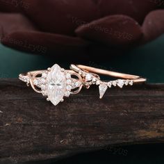 two gold rings with white diamonds on top of a piece of wood next to a pink rose