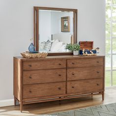 a dresser with a mirror on top of it in front of a wall and window